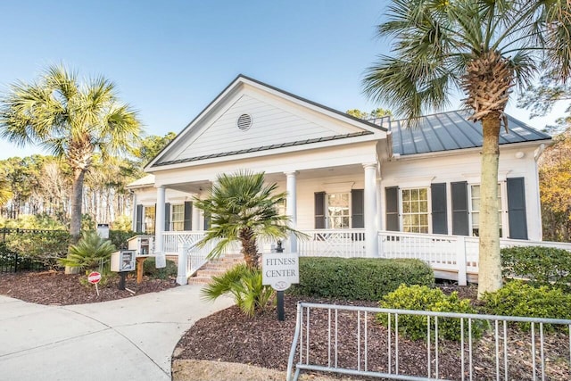 neoclassical home featuring a standing seam roof, a porch, and metal roof