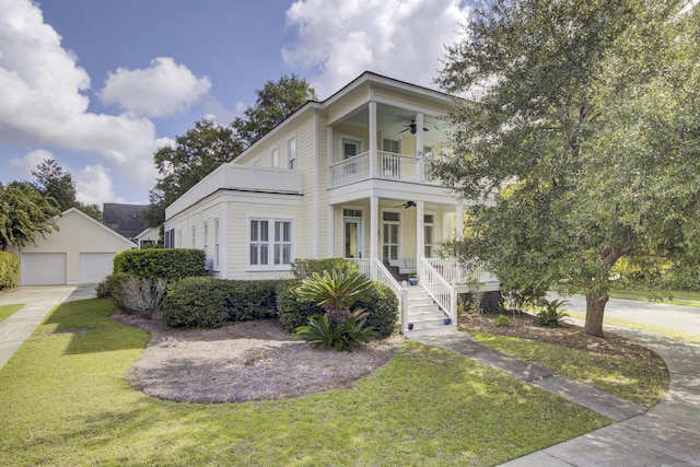 view of front of home featuring a ceiling fan, covered porch, an outdoor structure, a balcony, and a front lawn