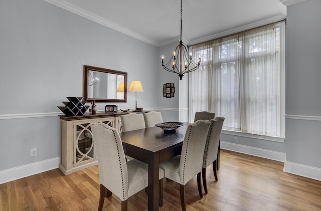 dining area featuring ornamental molding, baseboards, light wood finished floors, and a notable chandelier