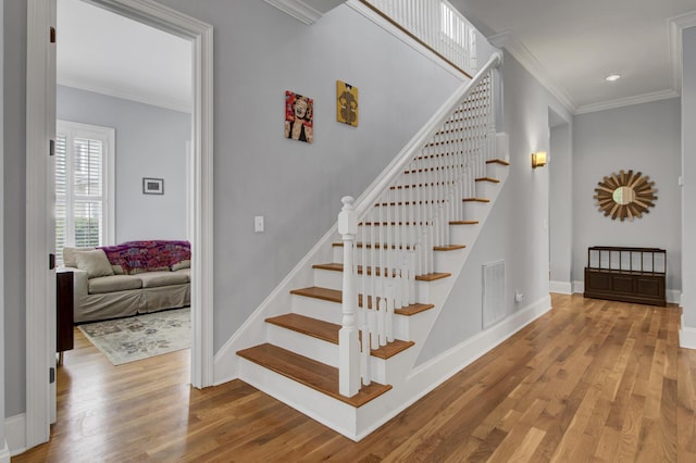 stairway featuring crown molding, baseboards, and wood finished floors