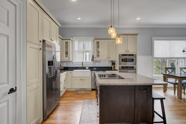kitchen with light wood-style floors, a breakfast bar, a kitchen island, a sink, and stainless steel appliances