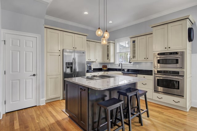 kitchen featuring glass insert cabinets, light wood-style flooring, a kitchen island, hanging light fixtures, and stainless steel appliances