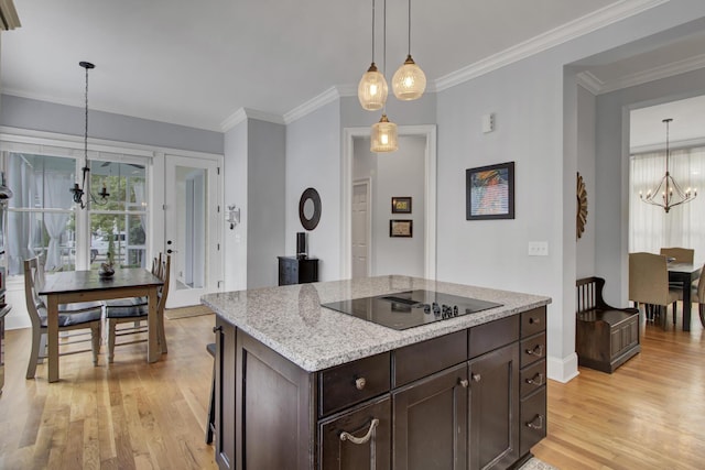 kitchen featuring dark brown cabinetry, light wood-type flooring, ornamental molding, a notable chandelier, and black electric cooktop