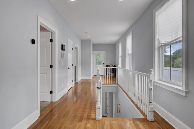corridor featuring recessed lighting, baseboards, an upstairs landing, and wood finished floors