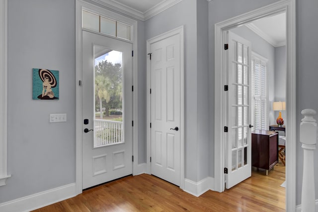 foyer with light wood-type flooring, a healthy amount of sunlight, and ornamental molding