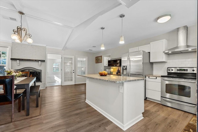 kitchen featuring a center island, wall chimney range hood, white cabinetry, appliances with stainless steel finishes, and beamed ceiling