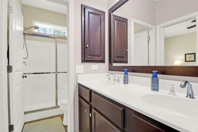 full bath with double vanity, a stall shower, toilet, and a sink