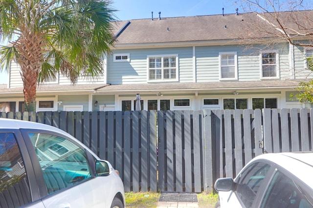 view of side of property featuring a fenced front yard and a shingled roof