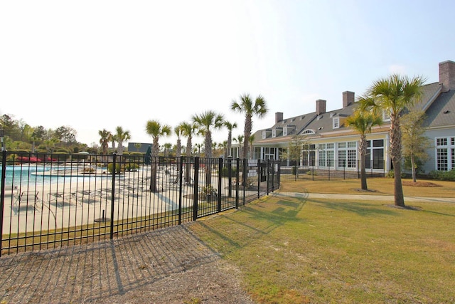 view of home's community with a lawn, a pool, and fence