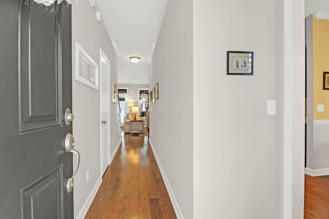 corridor featuring baseboards and hardwood / wood-style floors