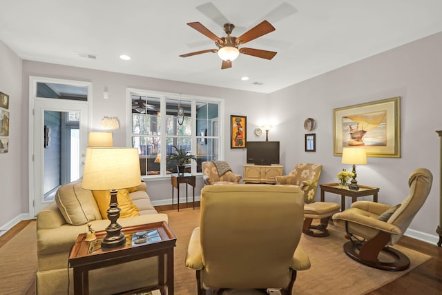 living room with visible vents, baseboards, wood finished floors, and a ceiling fan