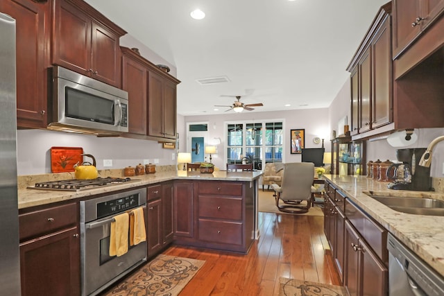 kitchen featuring visible vents, a sink, dark wood-style floors, appliances with stainless steel finishes, and a peninsula