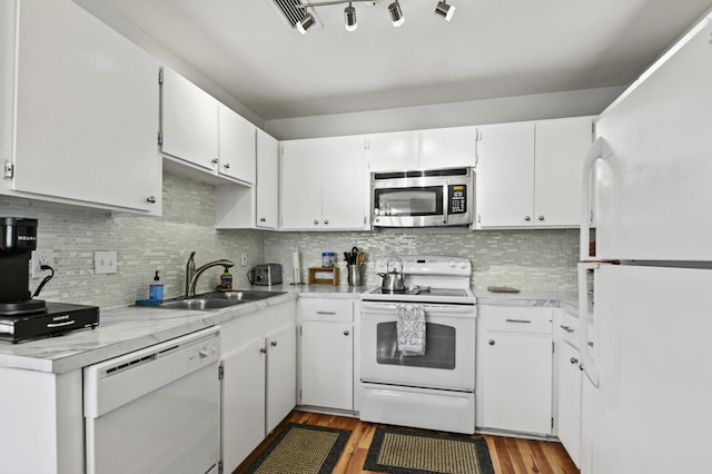 kitchen featuring a sink, light wood-style floors, white appliances, light countertops, and tasteful backsplash