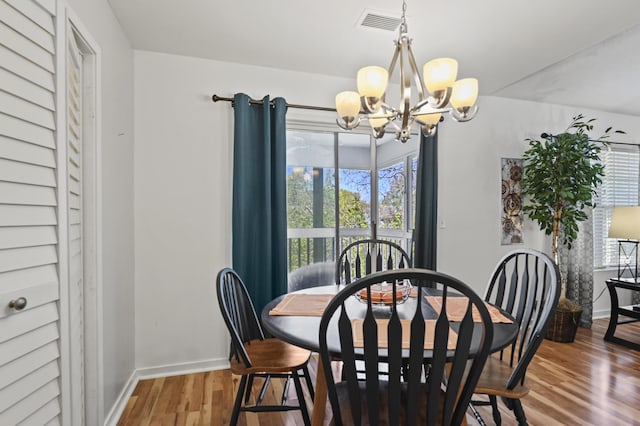 dining area with baseboards, a chandelier, wood finished floors, and visible vents