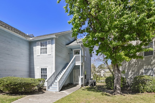 doorway to property featuring central air condition unit and a lawn