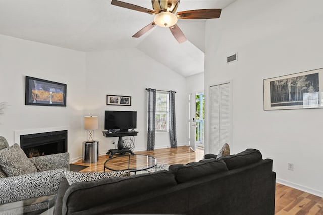 living room with visible vents, wood finished floors, a fireplace, baseboards, and a ceiling fan
