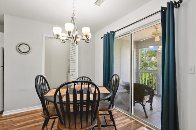 dining area with baseboards, visible vents, wood finished floors, and ceiling fan with notable chandelier