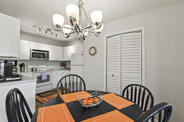 dining room featuring visible vents, wood finished floors, and a notable chandelier