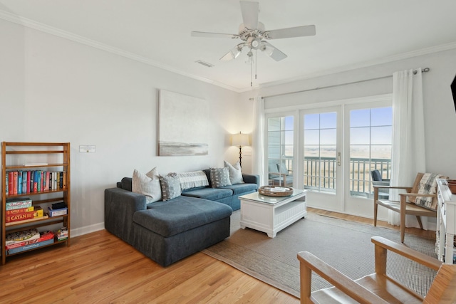 living area with light wood-type flooring, ceiling fan, ornamental molding, and baseboards