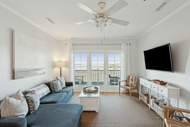 living area featuring ceiling fan, visible vents, and ornamental molding