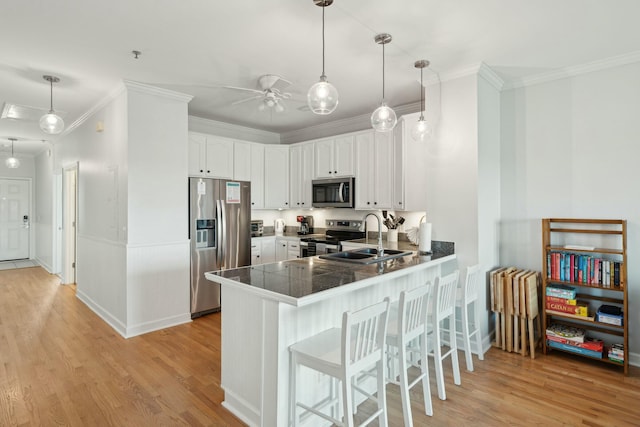 kitchen featuring light wood-style flooring, appliances with stainless steel finishes, a peninsula, white cabinetry, and a sink