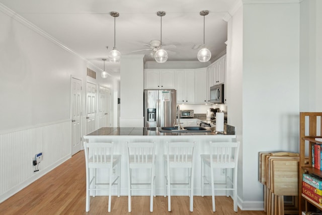 kitchen with stainless steel appliances, dark countertops, a peninsula, and a breakfast bar area