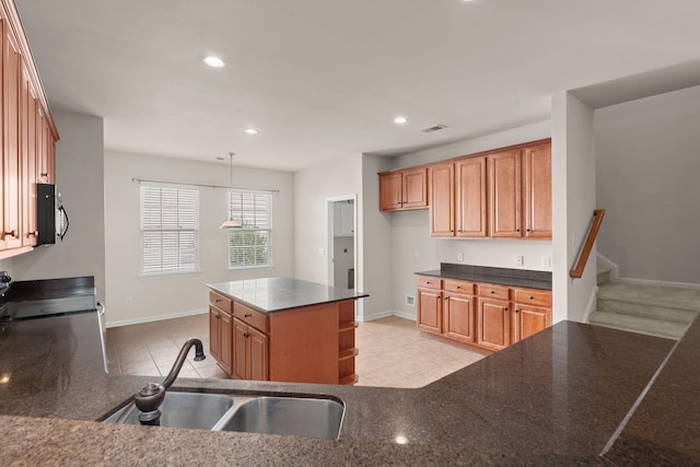 kitchen with a kitchen island, sink, hanging light fixtures, stove, and light tile patterned floors