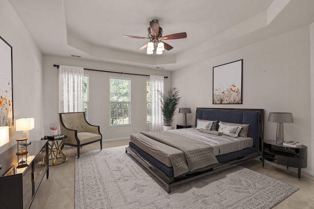 carpeted bedroom with ceiling fan and a tray ceiling