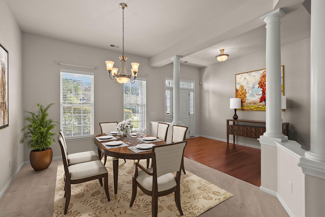 carpeted dining space with decorative columns and a notable chandelier