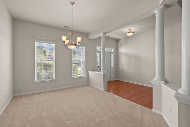 spare room with an inviting chandelier, light colored carpet, and decorative columns