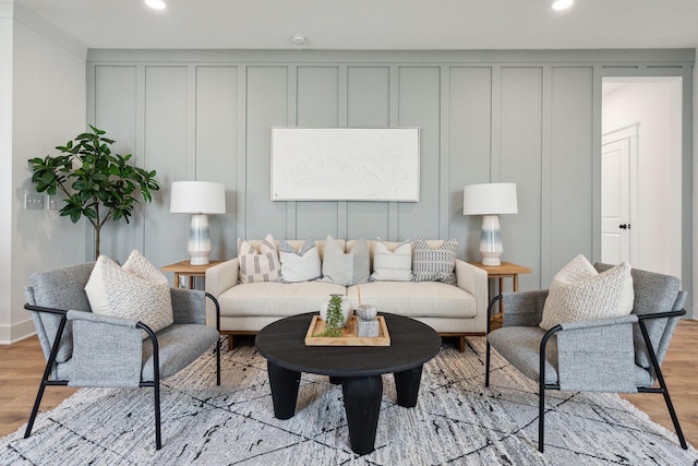 living area with a decorative wall, recessed lighting, and light wood-style flooring