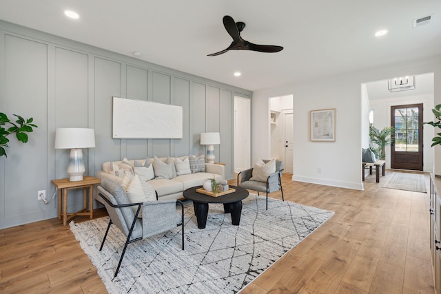 living area featuring recessed lighting, a decorative wall, light wood-type flooring, ceiling fan, and visible vents