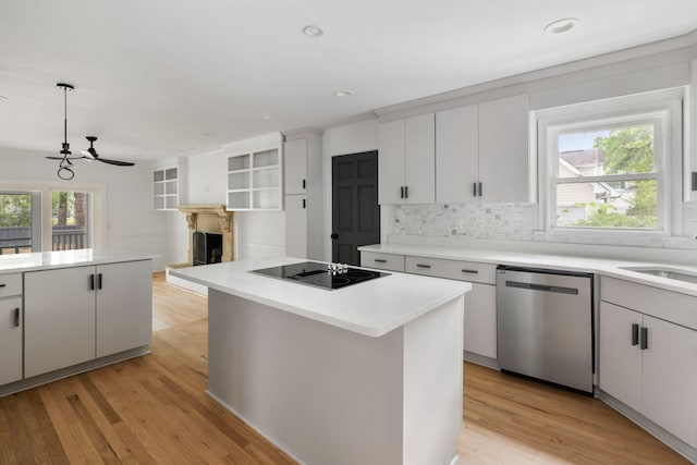 1019 Royalist Rd, Mount Pleasant, SC 29464 - kitchen featuring stainless steel dishwasher, black electric stovetop, a fireplace with raised hearth, tasteful backsplash, and light wood-style floors