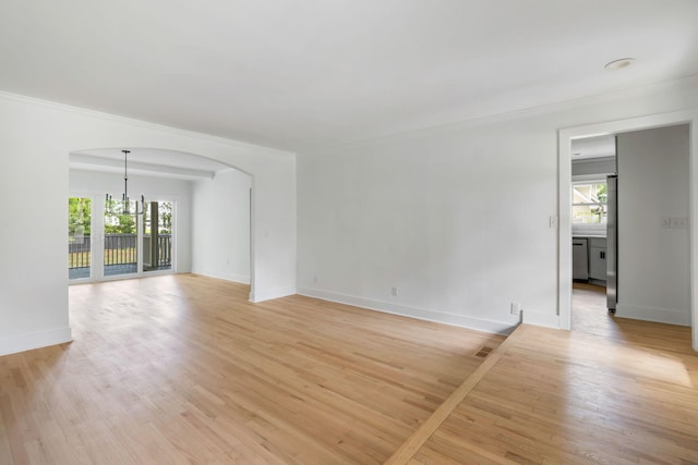 1019 Royalist Rd, Mount Pleasant, SC 29464 - unfurnished living room featuring plenty of natural light, a chandelier, ornamental molding, arched walkways, and light wood-style flooring