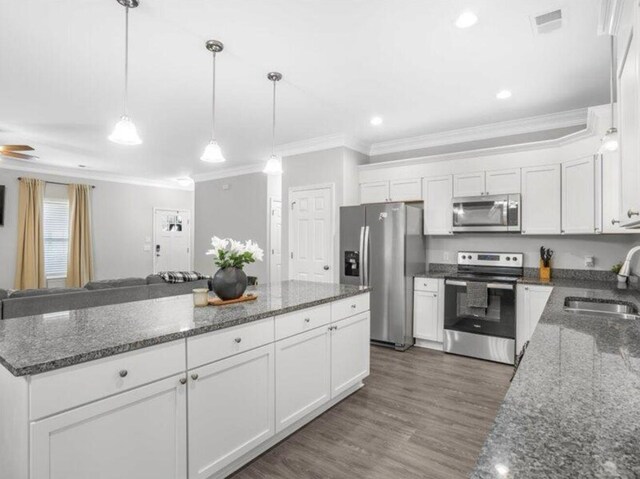 kitchen with stainless steel appliances, white cabinetry, sink, and pendant lighting