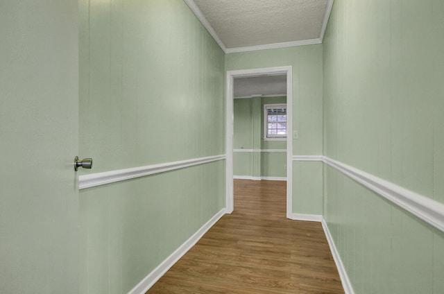 hall with hardwood / wood-style floors, a textured ceiling, and ornamental molding