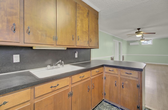 kitchen featuring ceiling fan, sink, kitchen peninsula, a textured ceiling, and hardwood / wood-style flooring