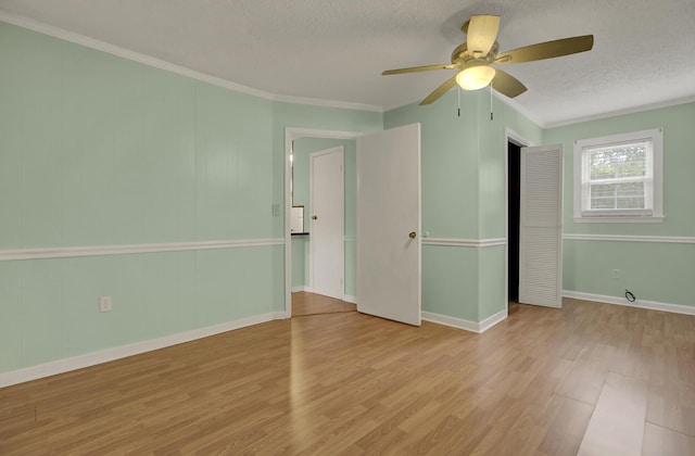 empty room featuring ceiling fan, light hardwood / wood-style floors, a textured ceiling, and ornamental molding