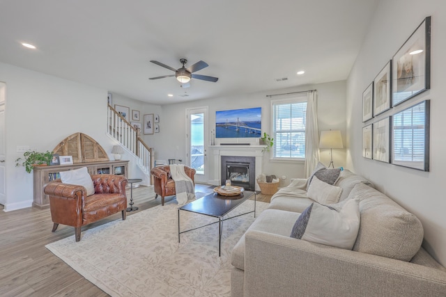 living area featuring wood finished floors, recessed lighting, a premium fireplace, ceiling fan, and stairs