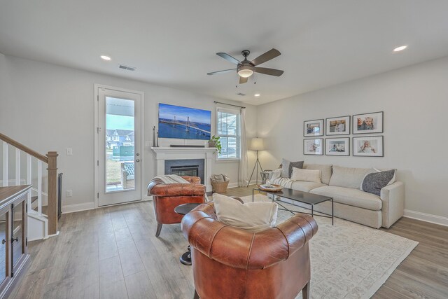 living room with stairway, wood finished floors, visible vents, recessed lighting, and a glass covered fireplace