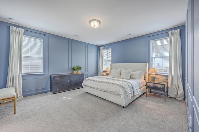 carpeted bedroom featuring a decorative wall and visible vents