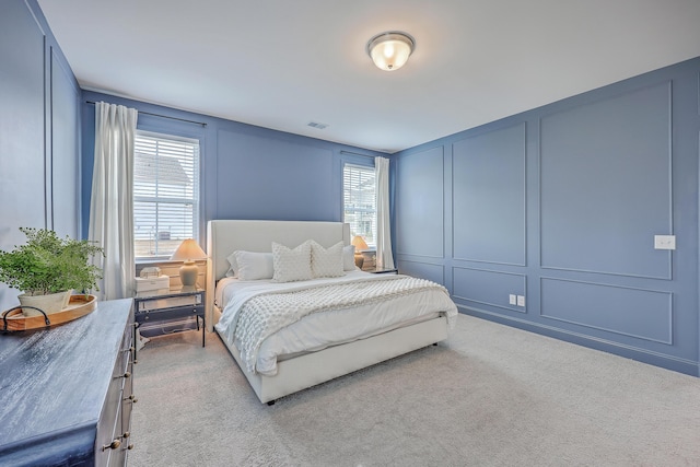 carpeted bedroom featuring a decorative wall and visible vents