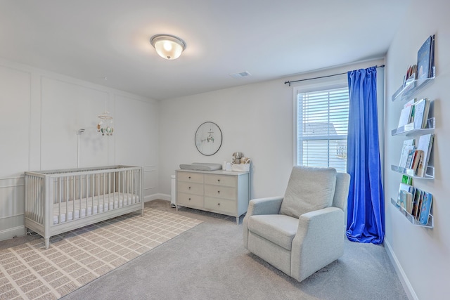 bedroom featuring visible vents, a nursery area, baseboards, and carpet