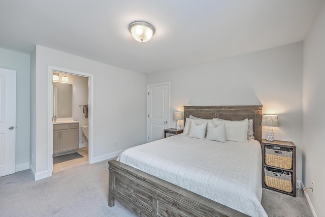 bedroom featuring light carpet, ensuite bath, and baseboards