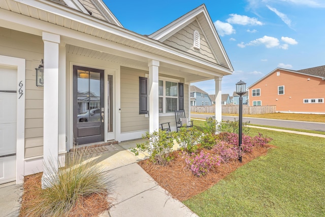 view of exterior entry featuring a porch and a lawn