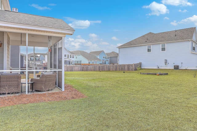 view of yard featuring central AC unit, fence, a residential view, and a sunroom