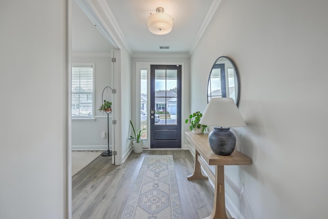 foyer entrance featuring baseboards, wood finished floors, visible vents, and ornamental molding