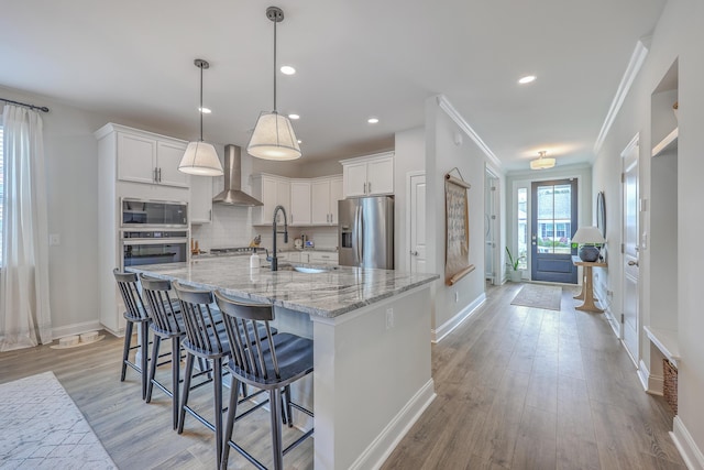 kitchen featuring decorative backsplash, appliances with stainless steel finishes, white cabinetry, and wall chimney exhaust hood