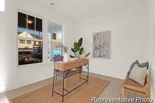 office space with wood finished floors, visible vents, and baseboards