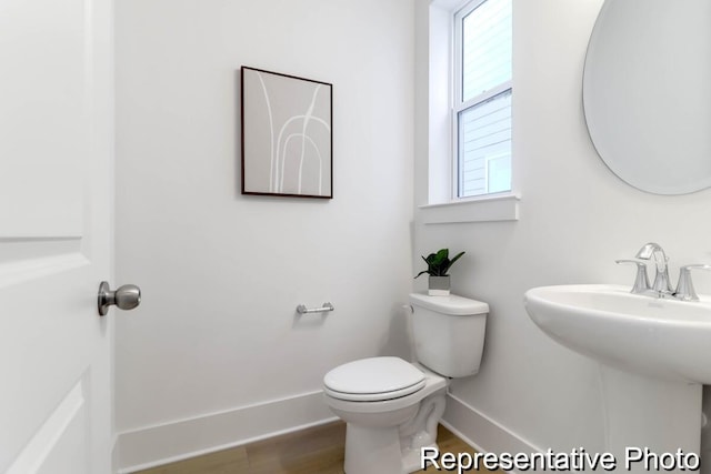 bathroom with toilet, baseboards, and wood finished floors